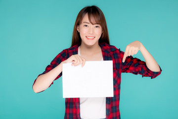 Beautiful portrait young asian woman presenting with blank paper sheet, asia girl wear travel summer fashion with happy pointing empty board or card isolated on blue background.
