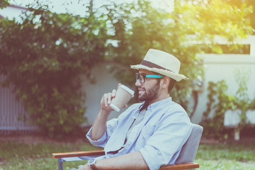 Fototapeta premium Caucasian man wearing hat and glasses drinking coffee at outdoor,Happy and smiling,Relaxing time