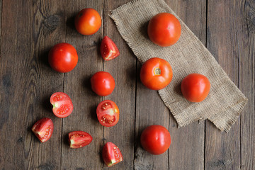 tomato fruits and sliced pieces on a wooden board.