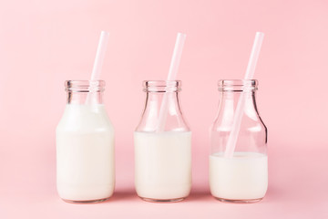 Three bottles of milk of yogurt on pink background.