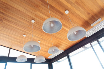 Modern ceiling lamp interior light bulbs against wooden wall background. Ceiling lamps are some of...