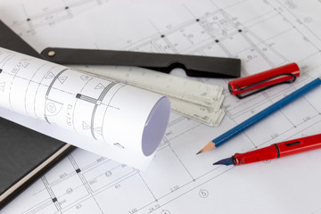 Rolls of architecture blueprints and house plans on the table and architect drawing tools.