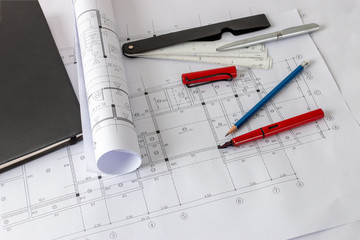 Rolls of architecture blueprints and house plans on the table and architect drawing tools.