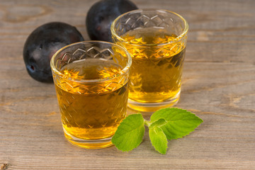 homemade sweet plum wine in glasses on wooden table