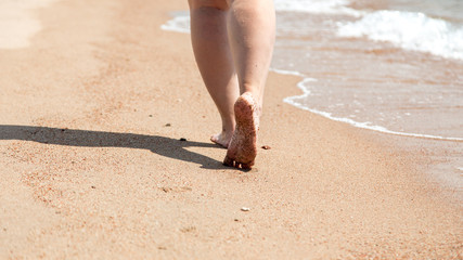 Closeup of bare feet on the beach. Walking on the sand at the water's edge. Vacation and travel concept.