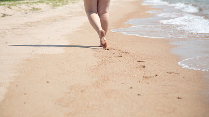 Closeup of bare feet on the beach. Walking on the sand at the water's edge. Vacation and travel concept.