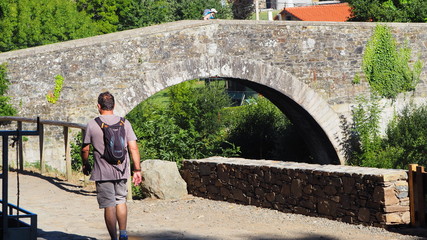 puente romano con una persona pasando y un hombre delante. furelos, la coruña