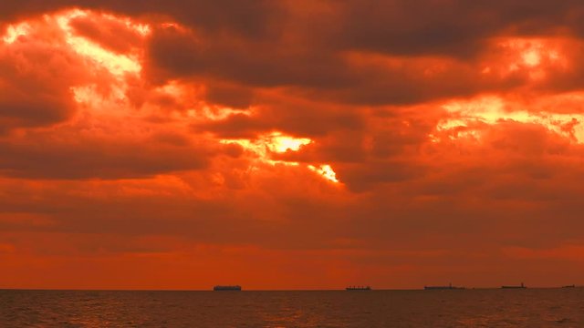 sunset orange yellow sky red storm cloud moving on sea and silhouette cargo ship and fishing boat moving