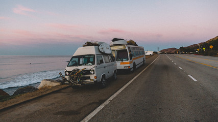 Vintage Camper Van and Bus Parked on a Coastal Road at Sunset