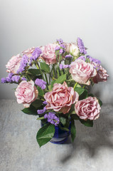 A bouquet of powdery pink roses on a gray background. Shades of soft purple.