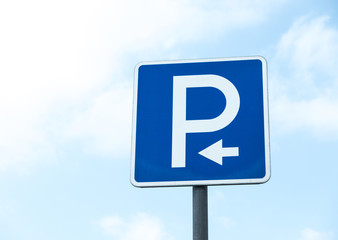 Road sign against the sky. White letter P on a blue background. Sign "Parking". Summer day.