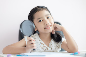 Little Asian girl using magnifier doing homework and smile with happiness for education concept select focus shallow depth of field