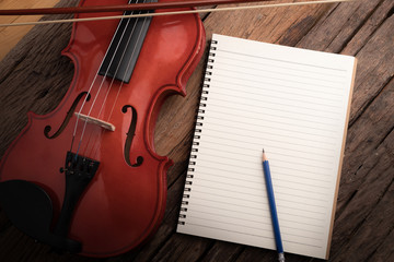 Fototapeta na wymiar Close-up shot violin orchestra instrumental and notebook over wooden background select focus shallow depth of field