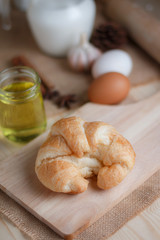Croissant on wooden cut board on table wood and fabric select focus shallow depth of field