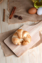 Croissant on wooden cut board on table wood and fabric select focus shallow depth of field
