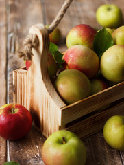 Ripe green and red apples in wooden box.