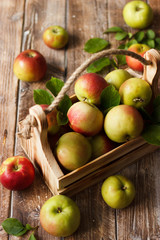 Ripe green and red apples in wooden box.