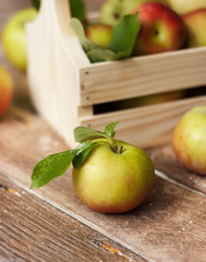 Ripe green and red apples in wooden box.
