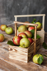 Ripe green and red apples in wooden box.