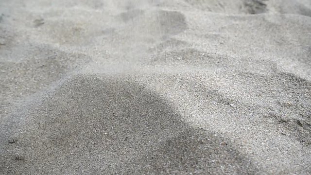 Slow motion sand trickle pours and forms a hill.