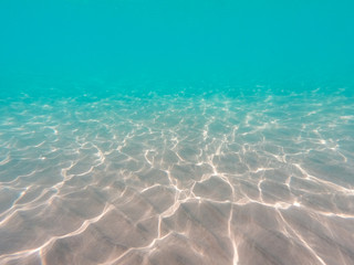 underwater background with sandy sea bottom. Beautiful texture of the sea and ocean water. Pure water texture.