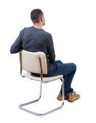 Side view of a man sitting on a chair.