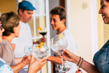 People toasting with glass and cocktails together in friendship - family have fun drinking beverages and smiling - concept of different ages and generations at home during celebration