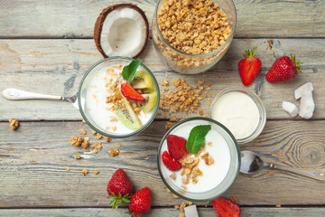 Healthy breakfast with yogurt, berries and granola on wooden table top view