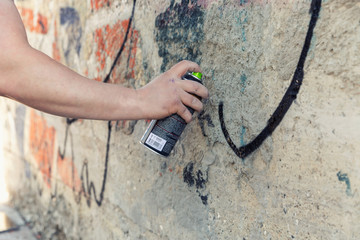 Graffiti Artist hands with paint cans against gray wall