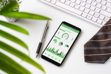 Top view of office desk table with graph chart on mock up smartphone on white desk table. Business management reports via mobile application concepts ideas. Mobk up mobile phone.
