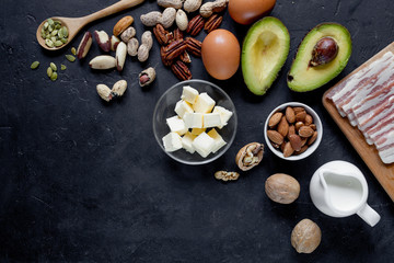 Obraz na płótnie Canvas Keto food: avocado, eggs, butter, bacon, nuts on dark background. 