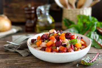 Beetroot or beet salad with boiled vegetables on wooden rustic table closeup