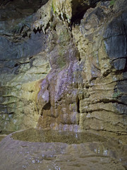 Geological rock formations and water pool in an underground cave