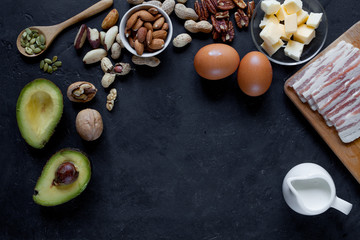 Keto breakfast: eggs, bacon, butter, tomatos,avocado, nutc, etc. on table. Flat lay. 