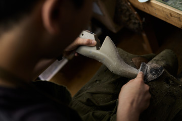 作業場で靴の型を削る靴職人