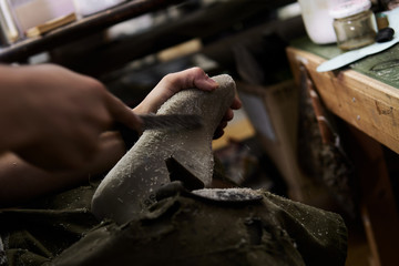 作業場で靴の型を削る靴職人