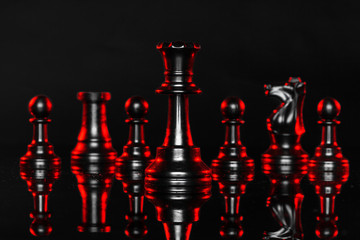 Chess pieces on dark background with red backlight close up