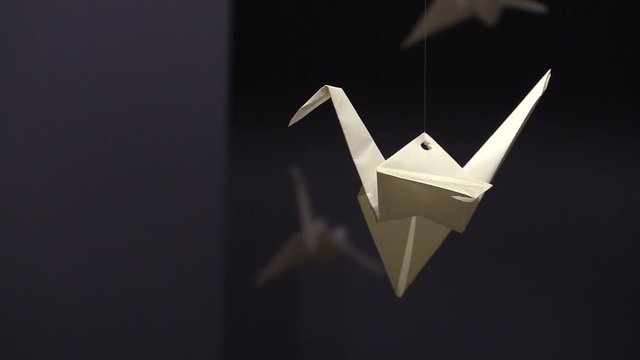 White Paper Origami Crane Hanging In a Dark Room