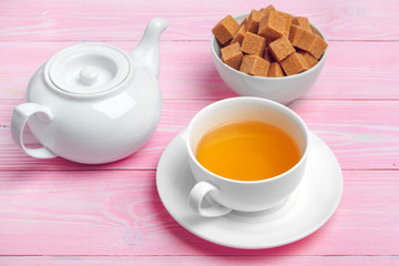 Cup of tea with sugar cubes and flower branches on wooden table close up