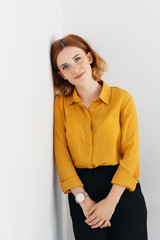 Calm young woman leaning against an interior wall