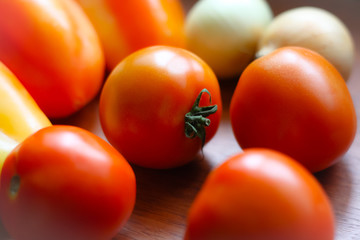 Ripe tomatoes, sweet peppers and onion on a wooden table