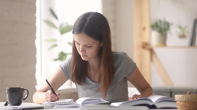 Woman student preparing for exam read textbook noting in notebook