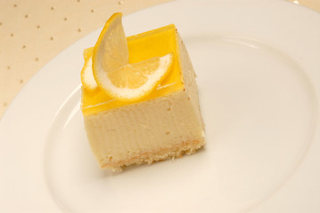 Slice of Lemon Cheesecake on white plate on the table