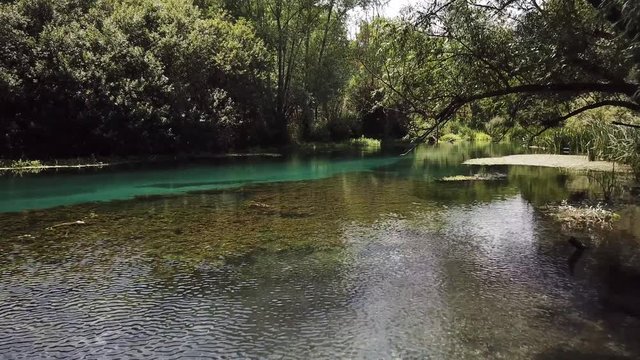 Low aerial drone clip over the crystal clear river Tirino in the Abruzzo region in Italy passing through the trees and lush vegetation.
