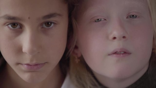 Close up portrait of brunette girl with brown eyes and albino girl with grey eyes looking at the camera. Concept of friendship. Carefree childhood. Contrast appearance