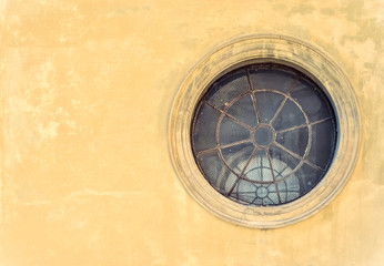 Round and vintage shape window on a ancient yellow wall 