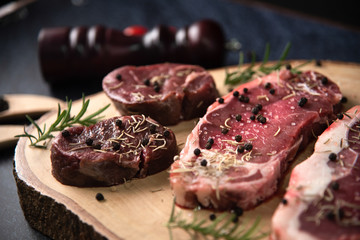 Fresh raw Prime Black Angus beef steaks on wooden board: Tenderloin, Denver Cut, Striploin, Rib Eye