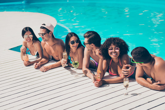 Photo of six multinational friends communicating in pool enjoying best company