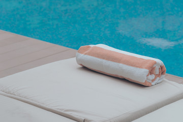 Roll soft towel on a sun bed near a swimming pool.