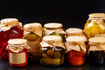  glass bottle with preserved food on black background